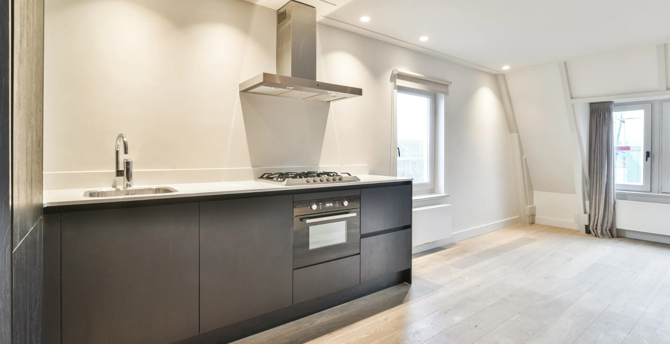 Sleek kitchen extension in Dallas TX with matte black cabinetry, integrated appliances, stainless steel range hood, and natural light from large windows.
